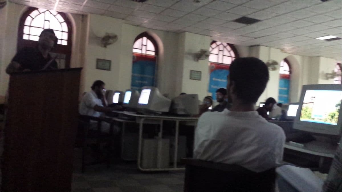 People at computers during a training workshop, with a presenter at a lectern.