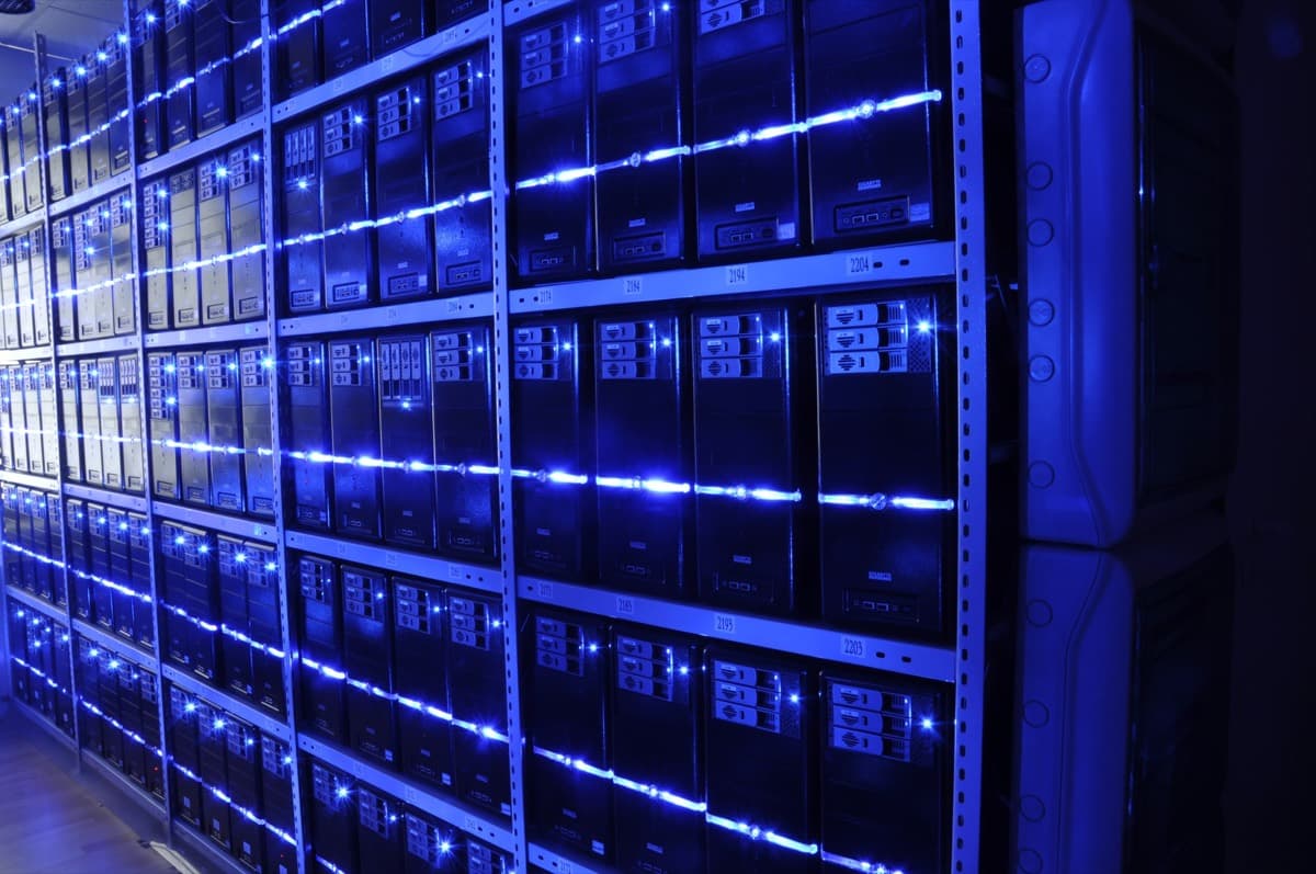 Rows of servers lit blue inside a data centre — the physical machines that 'the cloud' actually runs on.
